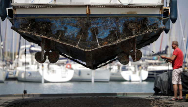 Photo : nettoyage de la coque d'un bateau dans le port de Leucate © Valentine Chapuis / Agence France-Presse.